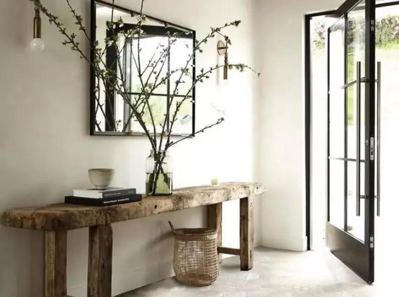 a hall in a domestic house with a wooden table on the left and the sun shining in through the open door on the right