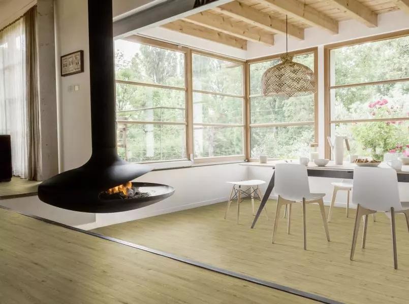 a kitchen with a stylish fireplace hanging from the ceiling. Chairs and dinging table on the right