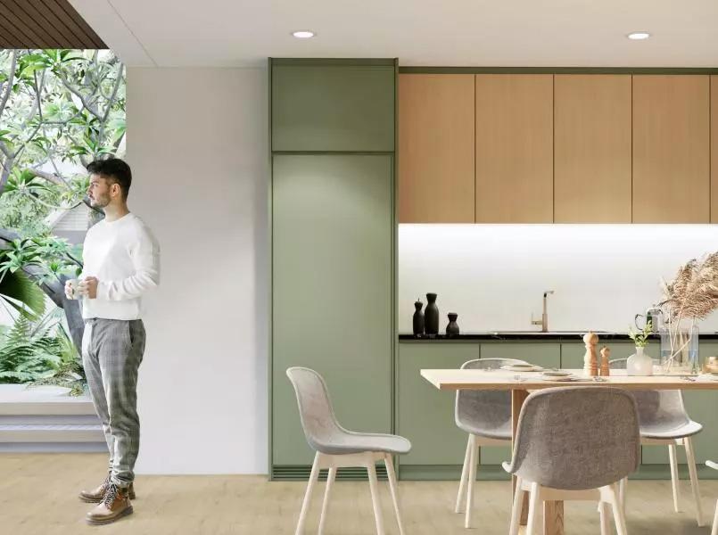 a man standing to the left in a kitchen. A combination of green and wooden kitchen fronts.