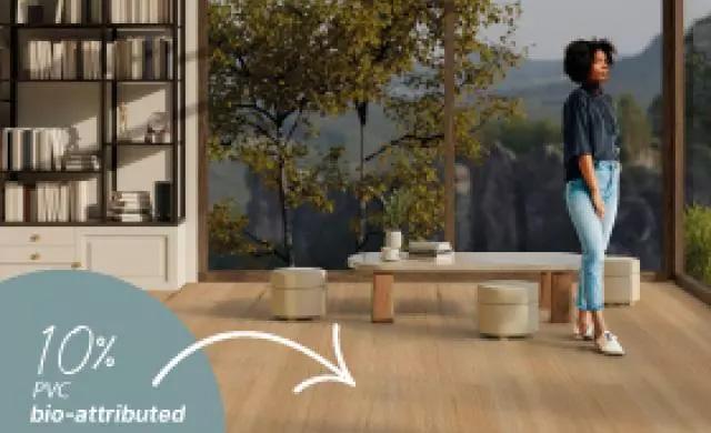 a woman standing in the living room with large windows in the background showing a great virew of nature. In the bottom left there is text saying 10% PVC bio-attributed