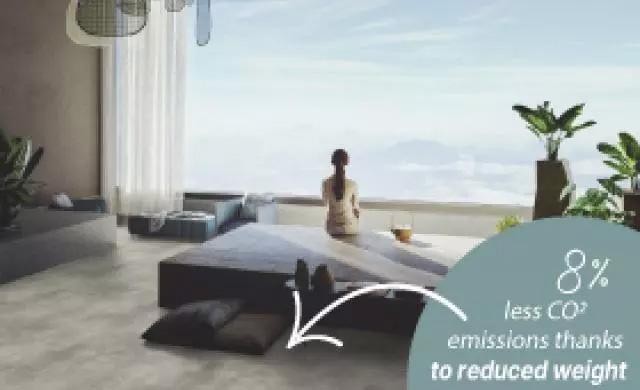 a woman sitting at the edge of the bed in a bedroom with a large window showing the blue sky outside